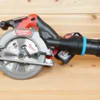 Black ToolCurve 2-1/2 inch hose adapter with blue ring joining a vacuum hose to a Milwaukee M18 circular saw