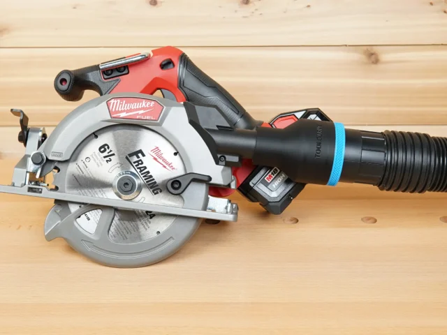 Black ToolCurve 2-1/2 inch hose adapter with blue ring joining a vacuum hose to a Milwaukee M18 circular saw