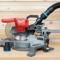 Black ToolCurve 2-1/2" hose adapter with blue band on a Milwaukee miter saw dust port, second adapter beside it