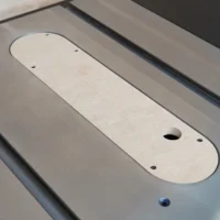 Light tan MDF zero clearance insert for Ridgid R4560 table saw, mounted in saw with visible mounting holes and central blade opening