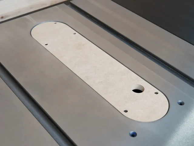 Light tan MDF zero clearance insert for Ridgid R4560 table saw, mounted in saw with visible mounting holes and central blade opening