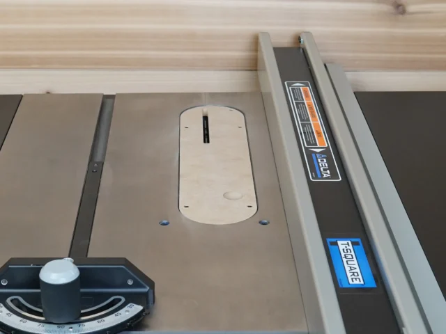 Cream-colored zero clearance insert installed in Delta Contractor table saw, with slot for blade visible and mounting holes exposed
