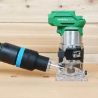 Black 36mm hose adapter with blue band linking a vacuum hose to the dust port of a green Metabo HPT trim router