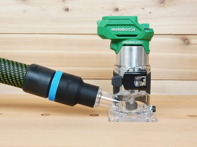 Black 36mm hose adapter with blue band linking a vacuum hose to the dust port of a green Metabo HPT trim router