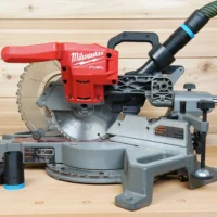 Black ToolCurve hose adapter with blue band installed on a Milwaukee M18 Fuel miter saw dust port, plus a second adapter beside the saw