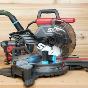 Black and blue ToolCurve hose adapter resting on a SKIL 10-inch miter saw table, with hose fitted to dust port