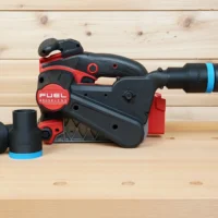 Black 36mm ToolCurve hose adapter with blue band on a Milwaukee M18 belt sander, second adapter beside it