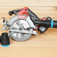 Black 36mm hose adapter with blue band installed on a Milwaukee M18 circular saw dust port, spare adapters alongside