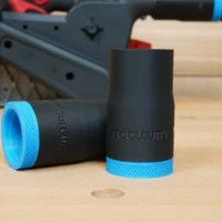 Two black hose adapters with blue grip bands, one shown upright and one laying on its side, labeled ToolCurve for Milwaukee M18 belt sander dust port connection.