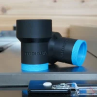 Black ToolCurve hose adapter with blue grip rings, shown as two cylindrical pieces on a work surface