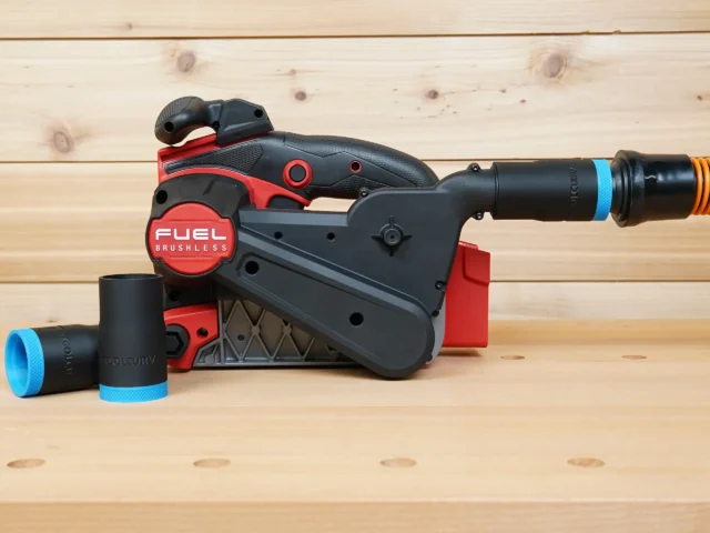 Black 1-1/4" hose adapter with blue band fitted to a Milwaukee M18 belt sander dust port, spare adapter beside it