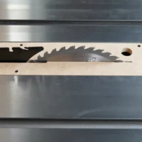 Light wood zero clearance insert with curved edges and saw blade cutout, mounted on metal table saw top