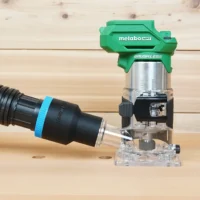 Black ToolCurve 1-7/8 inch hose adapter with blue band linking a vacuum hose to a green Metabo HPT trim router
