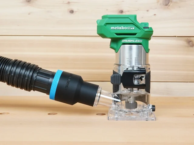 Black ToolCurve 1-7/8 inch hose adapter with blue band linking a vacuum hose to a green Metabo HPT trim router