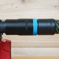 Black hose adapter with blue band attached to Milwaukee M18 belt sander dust port, connected to green and black braided hose