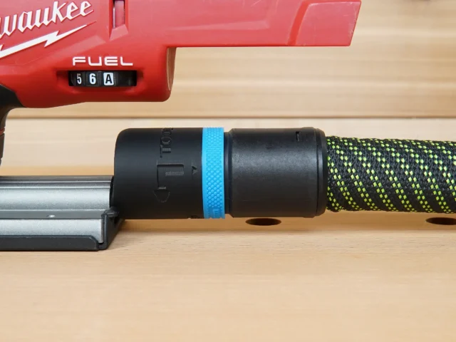 Black hose adapter with blue band attached to Milwaukee M18 Fuel jig saw dust port, with braided hose connected