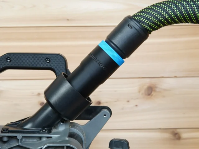 Black hose adapter with blue band attached to Milwaukee 7-1/4" cordless miter saw rear dust port, braided hose connected above