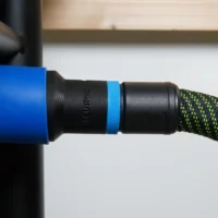 Black hose adapter with blue band attached to blue Delta table saw dust port, connected to black and green braided hose
