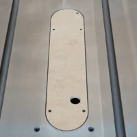Zero clearance insert for Ridgid R4560 table saw, light MDF panel with rounded ends and center blade slot, mounted between gray aluminum rails
