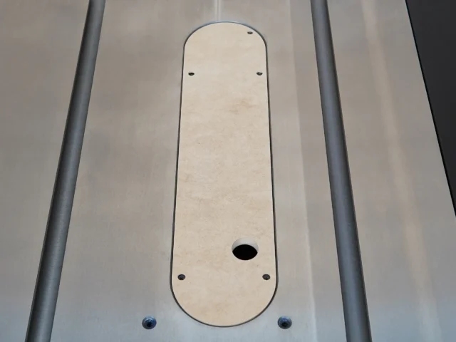 Zero clearance insert for Ridgid R4560 table saw, light MDF panel with rounded ends and center blade slot, mounted between gray aluminum rails
