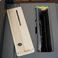 Cream-colored MDF zero clearance insert with slot and mounting holes, positioned next to SKIL table saw throat opening