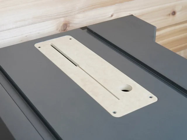 Cream-colored zero clearance insert with centered slot and mounting holes, positioned on gray SKIL table saw