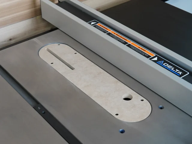 Zero clearance insert installed in Delta Contractor table saw, showing rounded MDF base with centered slot and mounting holes