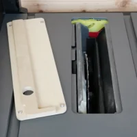 Zero clearance insert for SKIL 8-1/4" table saw, shown removed from saw table with interior openings visible, MDF construction with mounting holes and adjustment screw pocket