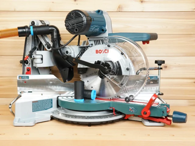 Black ToolCurve 1-1/4" hose adapter with blue band installed on a Bosch 10-inch glide miter saw dust port