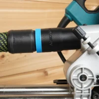 Black hose adapter with blue band attached to rear rail of Makita LS miter saw, connected to green and black braided hose
