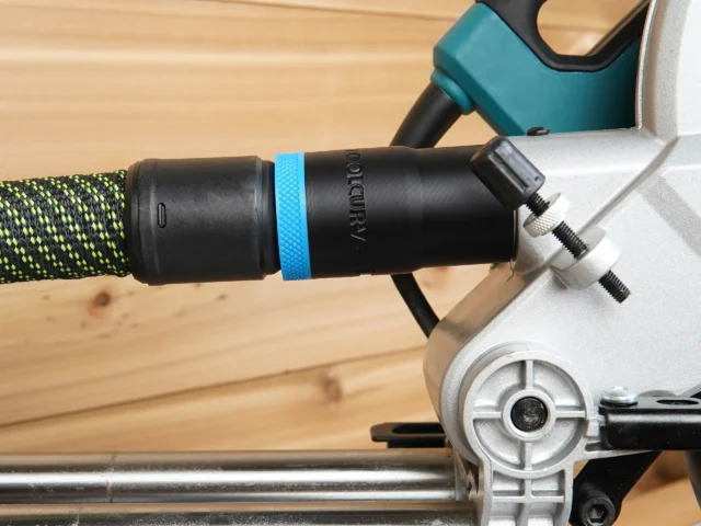 Black hose adapter with blue band attached to rear rail of Makita LS miter saw, connected to green and black braided hose