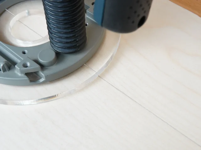 Clear acrylic router base plate attached to Bosch 1617 router, showing 8-inch diameter with mounting hardware and threaded hose connection visible.