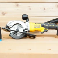 Black ToolCurve 1-7/8 inch hose adapter standing beside a Dewalt Atomic 20V 4-1/2 in. circular saw with hose attached