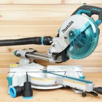 ToolCurve 1-7/8 inch hose adapter installed on a Makita LS miter saw dust port with hose attached, plus two spare adapters on the bench