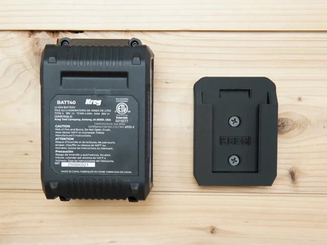 Black plastic battery mount for Kreg 18v battery, shown next to full-size Kreg BATT40 battery for scale