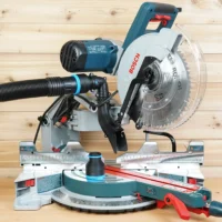 Black 2-1/2 inch hose adapter with blue ring joining a vacuum hose to a Bosch 12-inch glide miter saw dust port