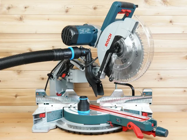 Black 2-1/2 inch hose adapter with blue ring joining a vacuum hose to a Bosch 12-inch glide miter saw dust port