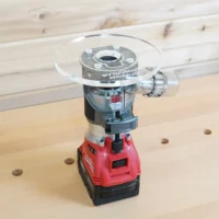 Clear 6-inch round acrylic router base plate with center bushing opening installed on a Milwaukee trim router