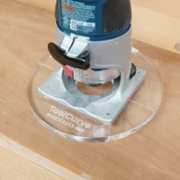 Clear acrylic router base plate mounted on Bosch Colt 1 HP trim router, showing 6-inch diameter and ruler marking on the base