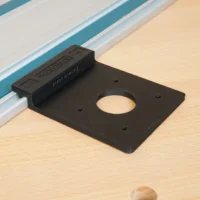 Black plastic rail adapter mounted on a Festool guide rail, with a circular opening and mounting holes visible from above