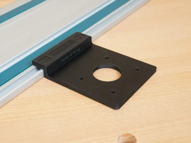 Black plastic rail adapter mounted on a Festool guide rail, with a circular opening and mounting holes visible from above