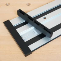 Black PETG protective caps installed on both ends of a Ryobi track saw aluminum guide rail, shown on a wooden workbench