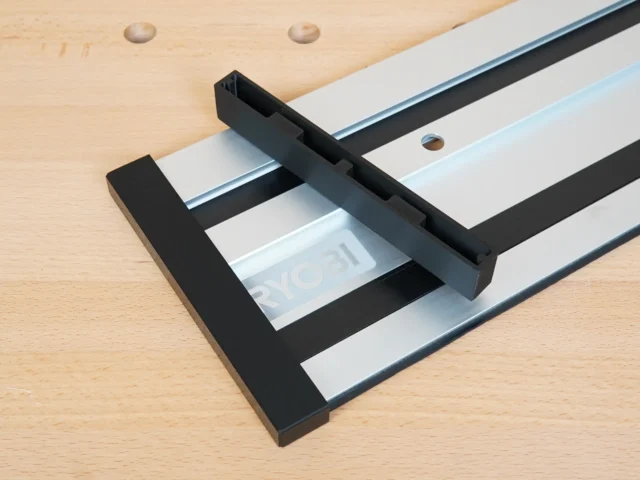 Black PETG protective caps installed on both ends of a Ryobi track saw aluminum guide rail, shown on a wooden workbench