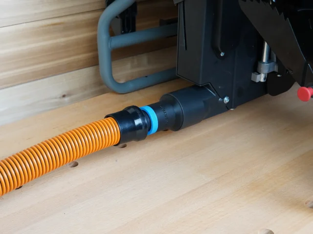Black 1-1/4 inch hose adapter with blue ring joining an orange shop vac hose to a Craftsman table saw dust port