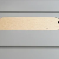 Light wood MDF zero clearance insert with rounded ends, four mounting holes, and a rectangular opening, positioned flat on a gray surface