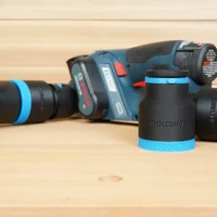 Black 36mm ToolCurve hose adapter with blue knurled ring standing beside a Bosch 12V MAX planer and hose