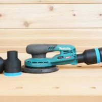 Black 36mm ToolCurve hose adapter installed on a Makita 40V XGT sander dust port, with a second adapter beside it