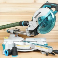 Black 36mm hose adapter installed on a Makita LS miter saw dust port with green hose, plus a spare adapter alongside