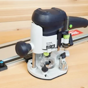 Festool OF 1010 EQ plunge router mounted on a guide rail with a black ToolCurve rail adapter and stop block