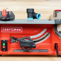 ToolCurve hose adapter with blue ring and black cylindrical body, displayed on Craftsman table saw dust port